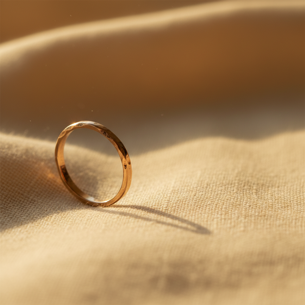A pair of hand-carved gold rings resting on warm linen